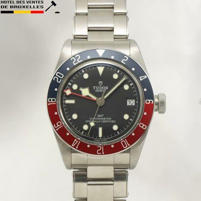 une montre en argent avec un cadran noir et une lunette rouge