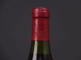 close up of a bottle of wine with a red cap on a black background