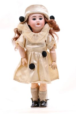 une petite poupée qui porte une robe et un chapeau