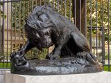 une statue de lion posée sur un socle devant une clôture