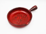 an old red bowl with writing on it sitting on a white surface