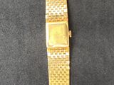 gold tone watch with a black band on a black surface