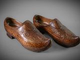 pair of carved wooden clogs on a gray surface