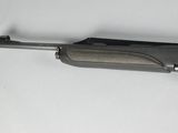 rifle on a white surface with a black handle and a gray body