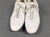 a pair of white tennis shoes on a grey surface