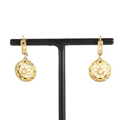 une paire de boucles d'oreilles en or posée sur un socle noir