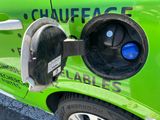 a green car with a fuel pump attached to it ' s side