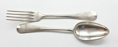 deux cuillères et une fourchette en argent sur une surface blanche
