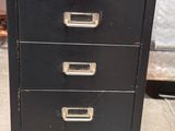 an old black filing cabinet with five drawers on top of it