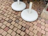 two white umbrellas sitting on the ground next to a potted plant