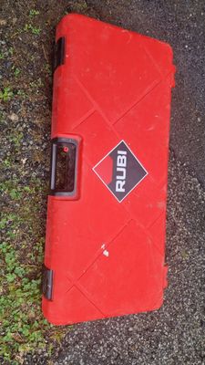 a red case sitting on the ground next to the grass
