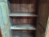 une armoire en bois dont la porte est ouverte, dans une pièce