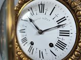 a gold clock with roman numerals on the face
