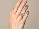 the woman ' s hand is holding a diamond ring in her left hand