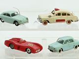 quatre voitures jouets dans une vitrine sur une surface blanche