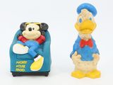 two figurines of donald and daisy duck on a white background