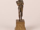 bronze figurine of a man holding a baseball bat on a pedestal