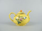 an old yellow teapot with flowers and leaves painted on it