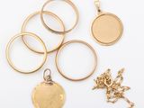 plusieurs types de bagues et de pendentifs en or posés sur un fond blanc