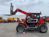 Un tracteur rouge est garé sur un parking avec une fourche