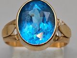 an image of a gold ring with a blue topaz stone