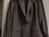 une veste de costume marron à fines rayures suspendue à un cintre dans une pièce