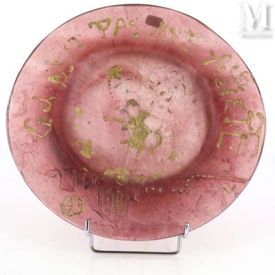une assiette rose avec une inscription dorée, posée sur un socle