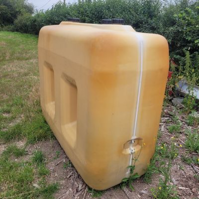 a large yellow water tank sitting in the middle of a field