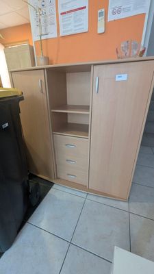 une poubelle noire posée à côté d'un meuble en bois