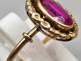 a close up of a gold ring with a pink stone in it