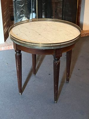 a small table with a marble top in front of a fireplace