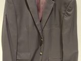 gray suit jacket hanging on a hanger on a white wall