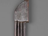 a metal comb with a long handle on a gray surface