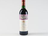 a bottle of red wine sitting on top of a white table