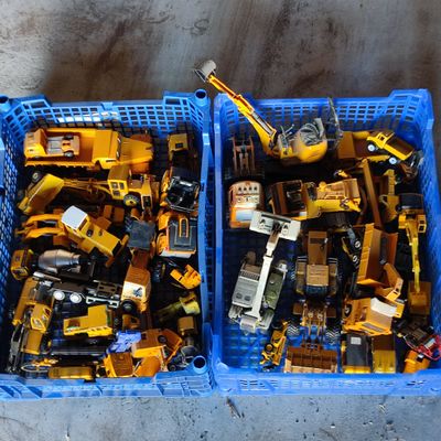 deux caisses remplies de petits engins de chantier en plastique posées par terre