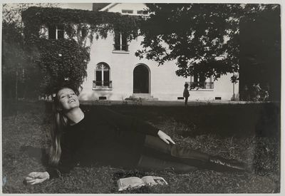 photographie en noir et blanc d'une femme allongée sur l'herbe devant un immeuble