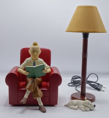 une figurine représentant un homme assis sur une chaise en train de lire un livre