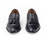 black leather loafers with tassels on a white background