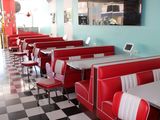 des tables et des banquettes dans un restaurant au sol à carreaux et aux murs bleus