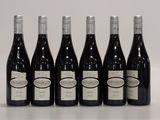 six bottles of wine are lined up on a white surface