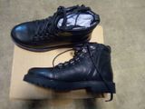 une paire de bottes en cuir noir à lacets posée sur une boîte en carton
