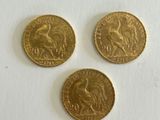 three gold coins sitting on top of a white surface next to each other