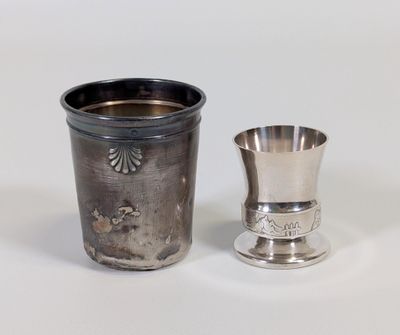 une coupe en argent à côté d'une autre coupe en argent, posées sur une surface blanche