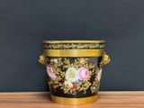 an image of a black and gold vase sitting on top of a wooden table