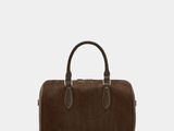 a brown handbag sitting on top of a white surface