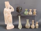 many vases and statues on a shelf with a gray background