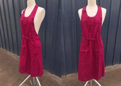 pair of red aprons on mannequins in front of a blue wall
