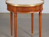 une petite table ronde avec un plateau en marbre et des finitions en laiton