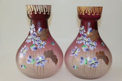 deux vases avec des fleurs peintes dessus, posés sur une table