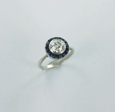 a close up of a diamond and sapphire ring on a white surface